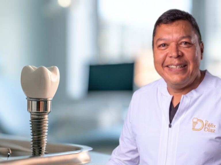 Dr. Félix Díaz, odontólogo especialista en implantes inmediatos en Caracas, en el consultorio del CCCT con pantalla de radiografía panorámica digital de fondo.